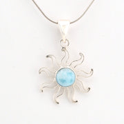 Silver sun-shaped pendant with a light blue center on a white background