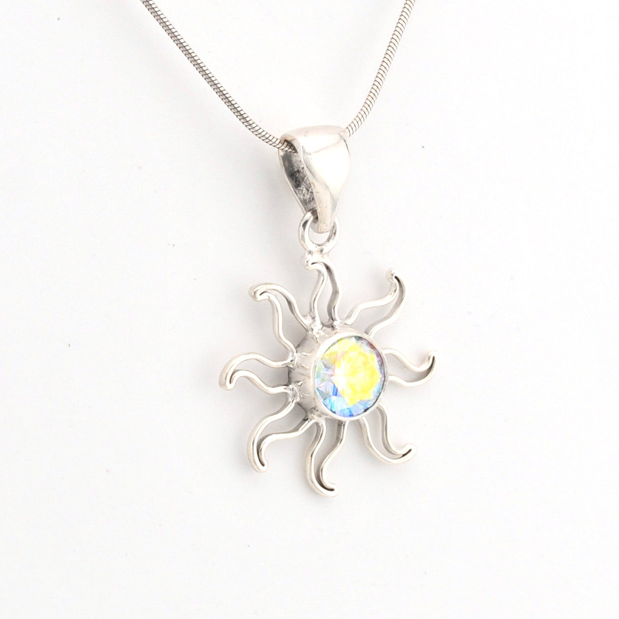 Silver sun-shaped pendant with a yellow gemstone on a white background