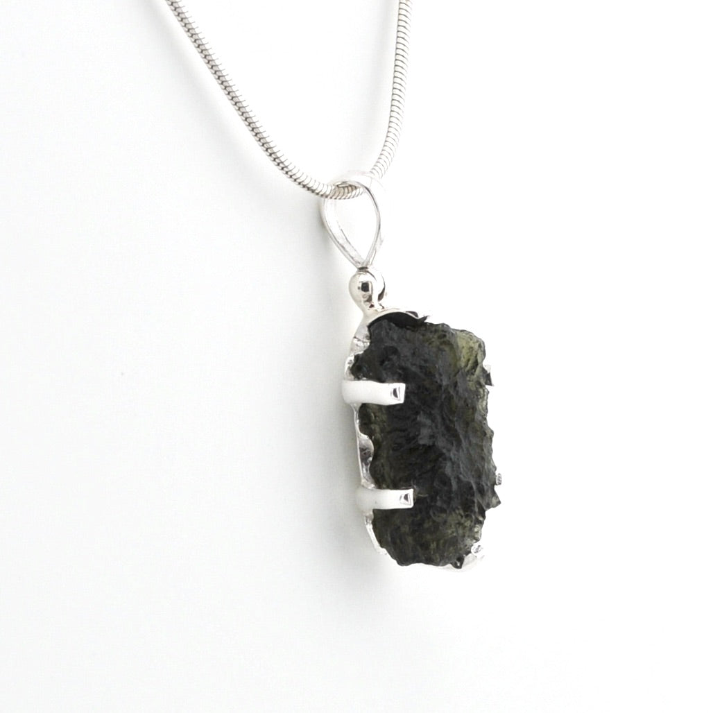 A silver snake chain necklace with a raw, rough dark green stone pendant held in a silver bezel setting, shown against a plain white background.