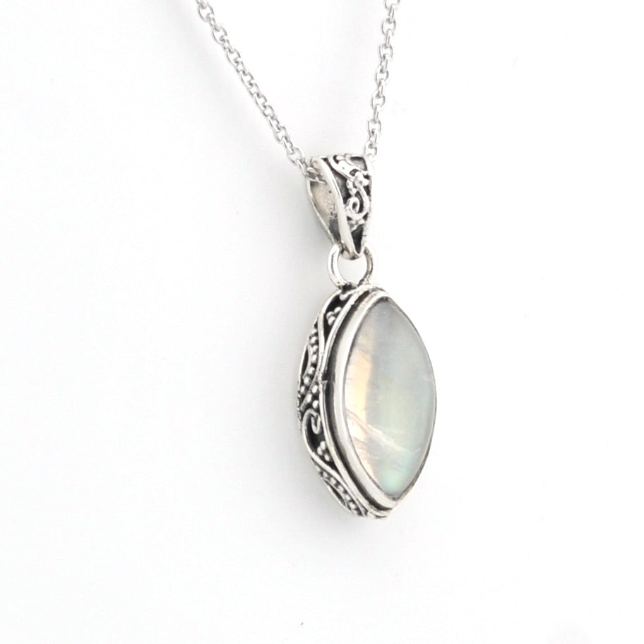 A silver pendant necklace featuring an oval iridescent moonstone gemstone in an ornate, filigree-set silver frame, suspended from a delicate silver chain against a plain white background.