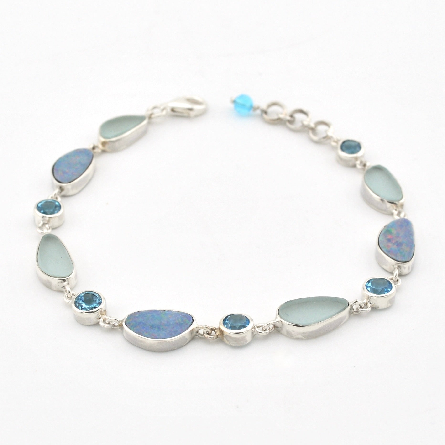 A silver link bracelet featuring large teardrop-shaped light blue-green opal stones and smaller round blue gemstone accents, displayed on a clean white background.