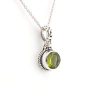 Silver pendant with a green gemstone on a white background