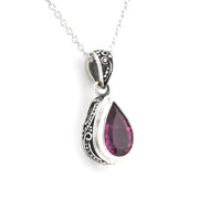 A silver teardrop pendant necklace featuring a faceted dark pink gemstone, set in an ornate silver bezel with a silver chain, shown against a plain white background.