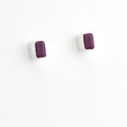 A pair of silver stud earrings with rectangular dark purple gemstones, shown on a plain white background.