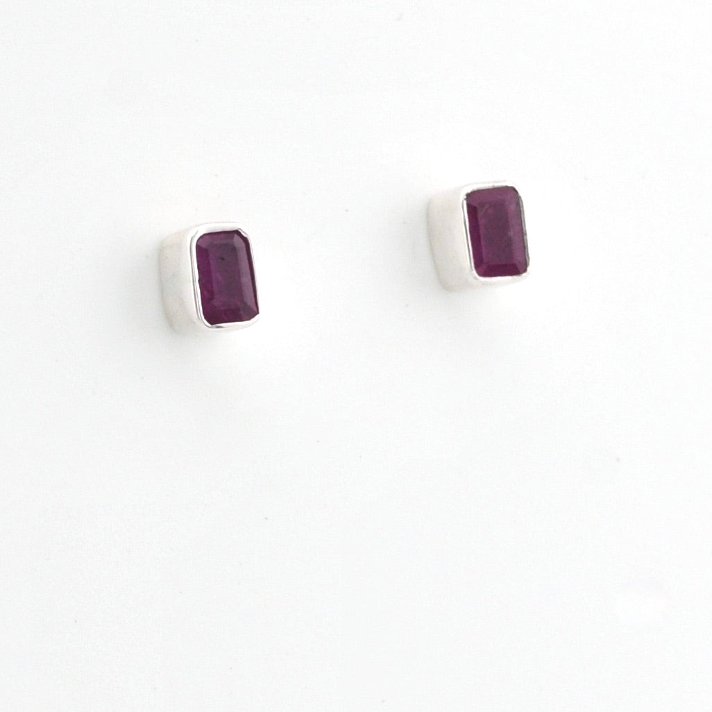 A pair of silver stud earrings with rectangular dark purple gemstones, shown on a plain white background.
