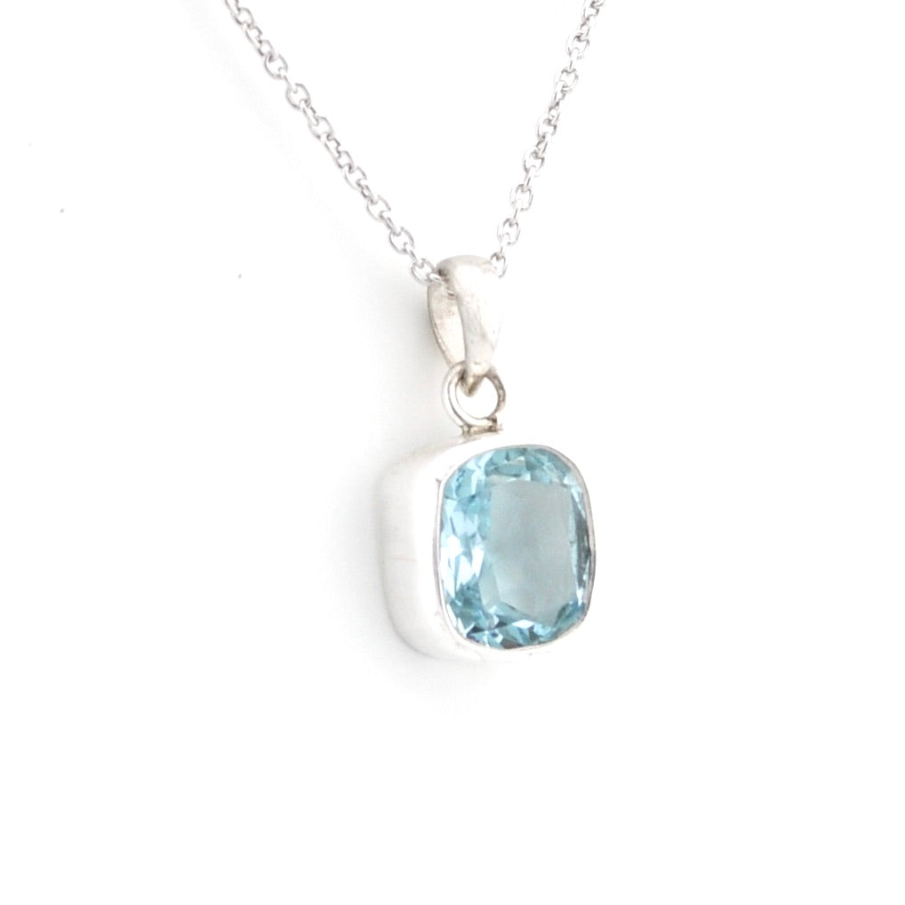 Blue topaz pendant with silver on chain on a white background