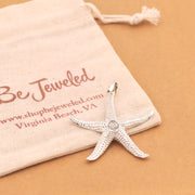 Silver starfish pendant on a Be Jeweled pouch with a beige background
