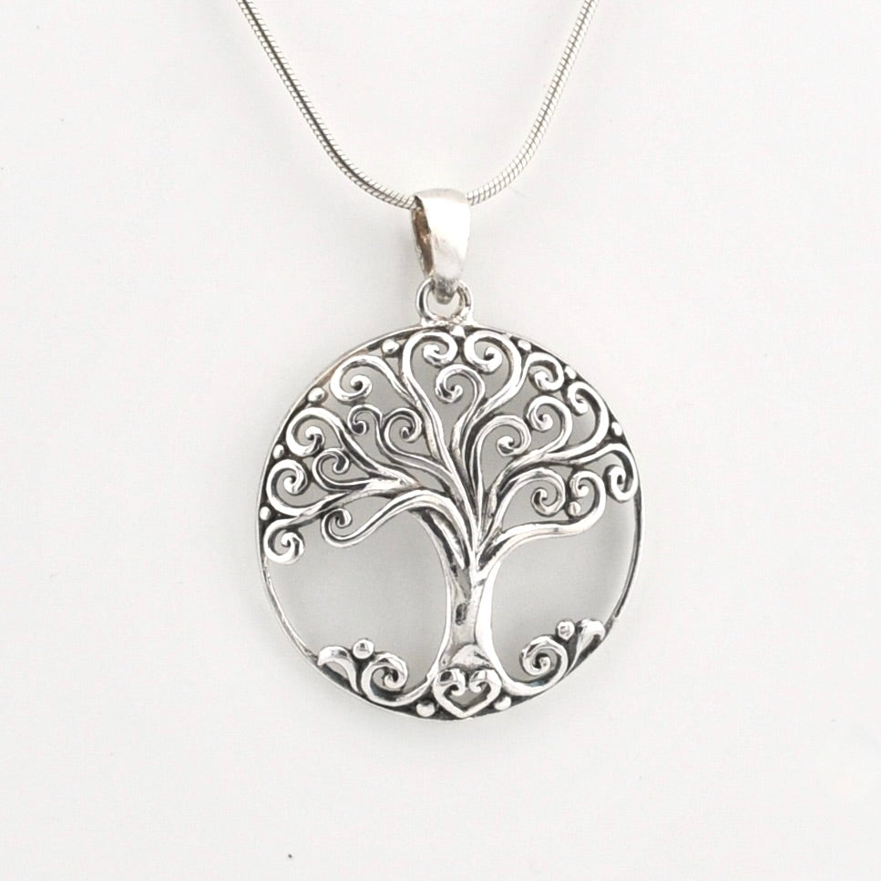 A silver pendant necklace featuring a circular tree of life design with intricate scrollwork, suspended from a fine silver chain against a plain white background.