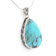 A teardrop-shaped turquoise pendant necklace with an ornate silver filigree border and a silver snake chain, shown on a plain white background.
