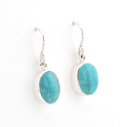 A pair of oval turquoise dangle earrings on a white background