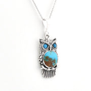 A sterling silver owl pendant necklace featuring a large oval turquoise stone with brown matrix inlay for the body, and two smaller round turquoise stones for the eyes, shown on a white background.