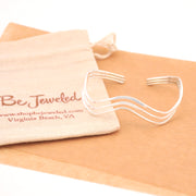 Silver bracelet on a beige cloth with 'Be Jeweled' branded pouch