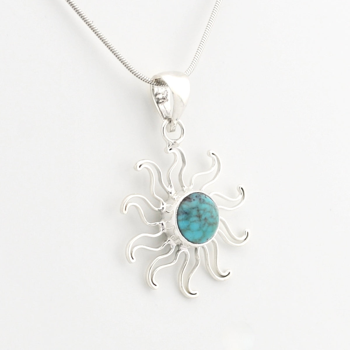 A silver sunburst pendant necklace featuring a round turquoise stone in the center, suspended from a delicate silver chain against a plain white background.