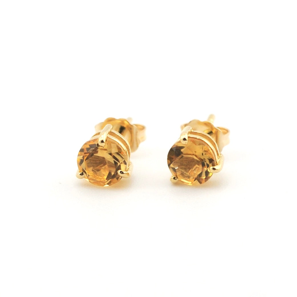 Pair of gold stud earrings with clear gemstones on a white background