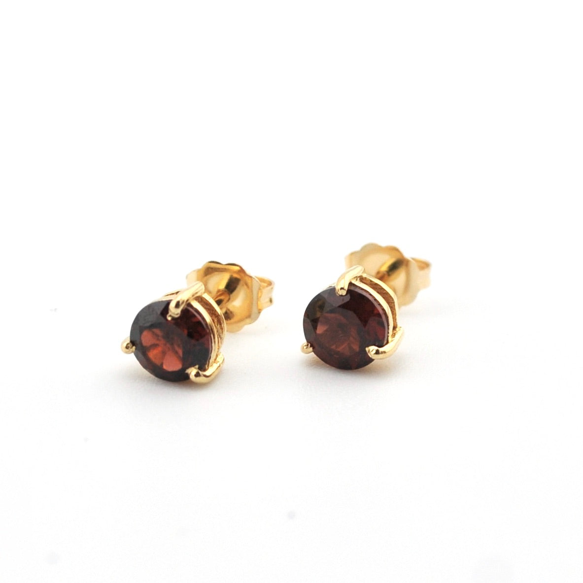 Gold stud earrings with red gemstones on a white background