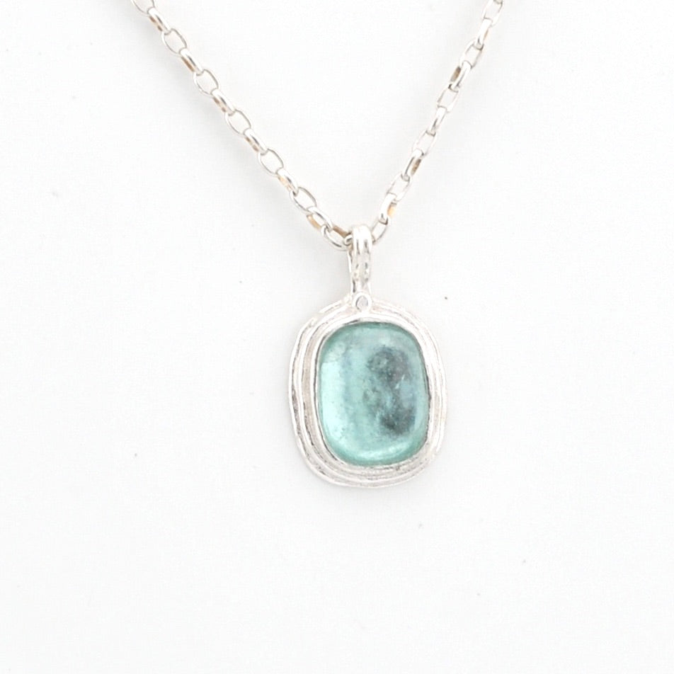 Necklace with a pendant featuring a aqua Roman glass on a white background