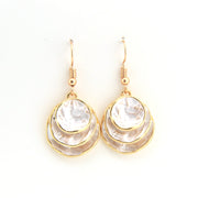 Pair of gold and white earrings on a white background