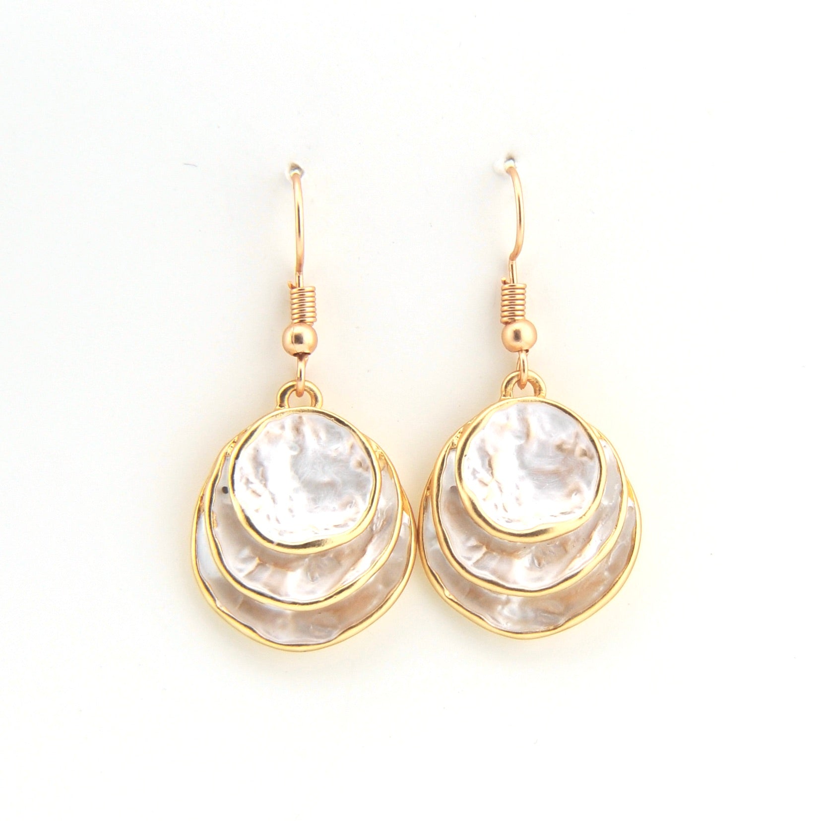Pair of gold and white earrings on a white background
