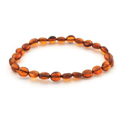 A beaded stretch bracelet made of polished oval amber beads in warm orange-brown tones, photographed on a clean white background.