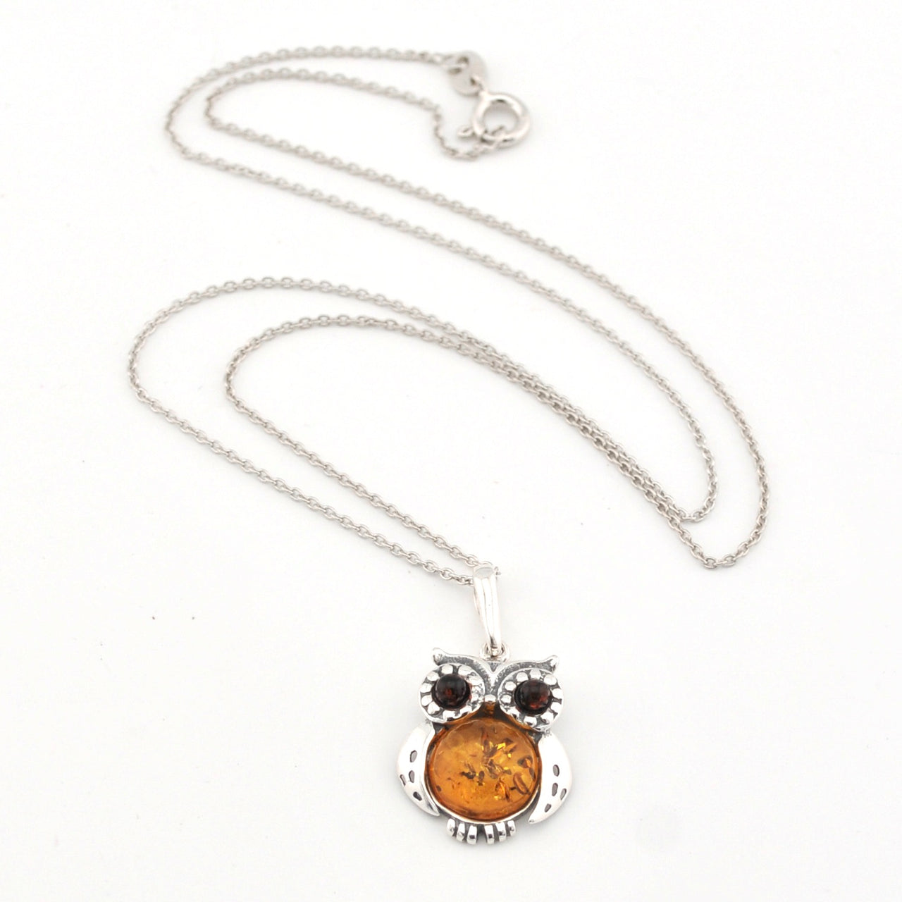 Silver owl pendant necklace with amber-colored stone on a white background