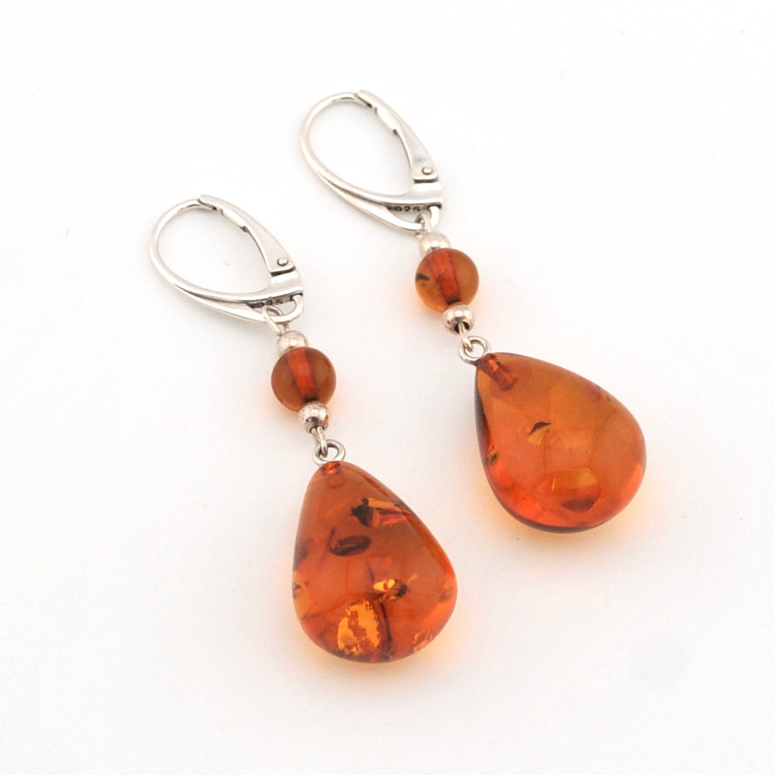 Pair of amber teardrop earrings with silver hooks on a white background