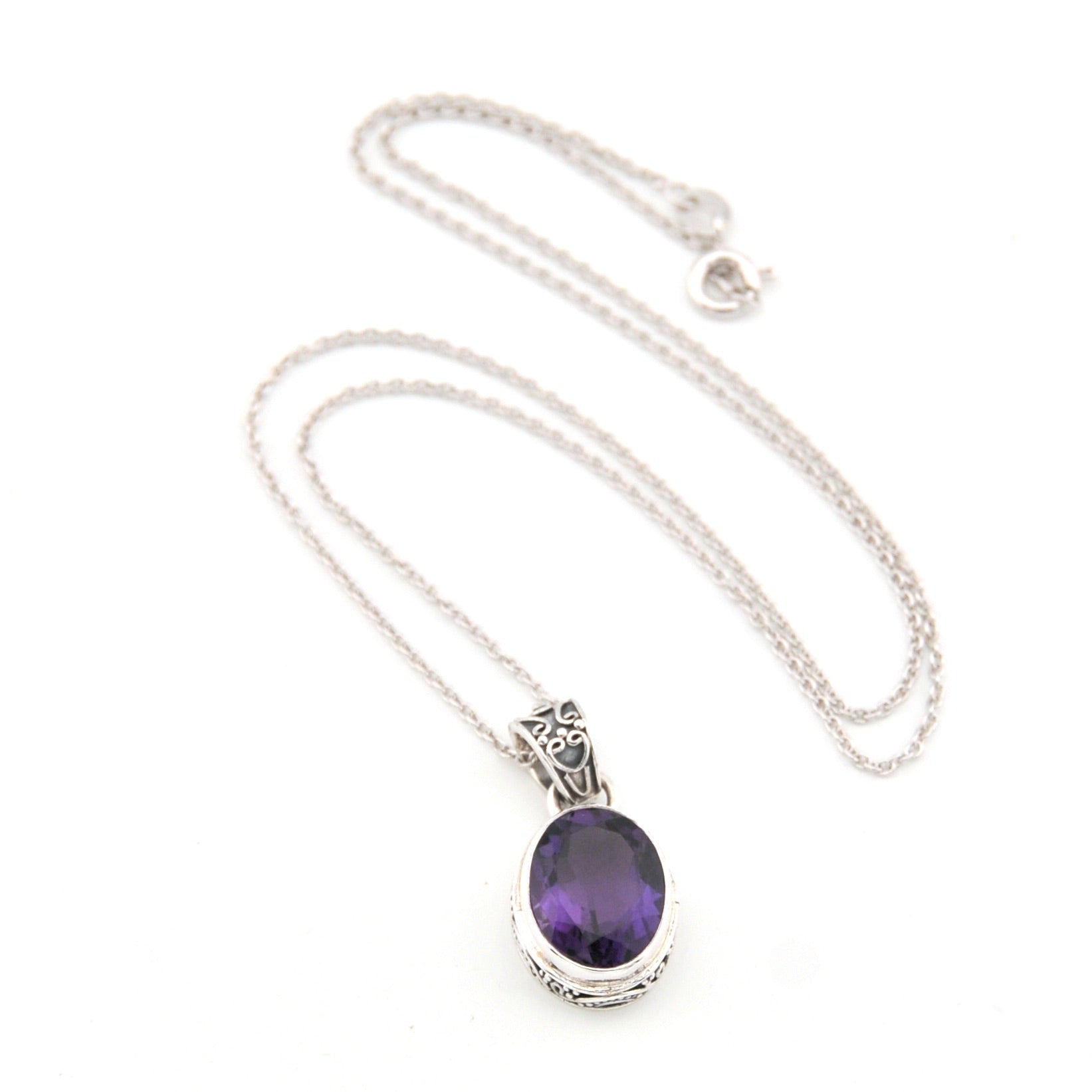 Silver necklace with a purple gemstone pendant on a white background