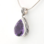 Purple teardrop pendant with silver setting on a white background