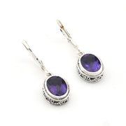 Silver earrings with purple gemstones on a white background