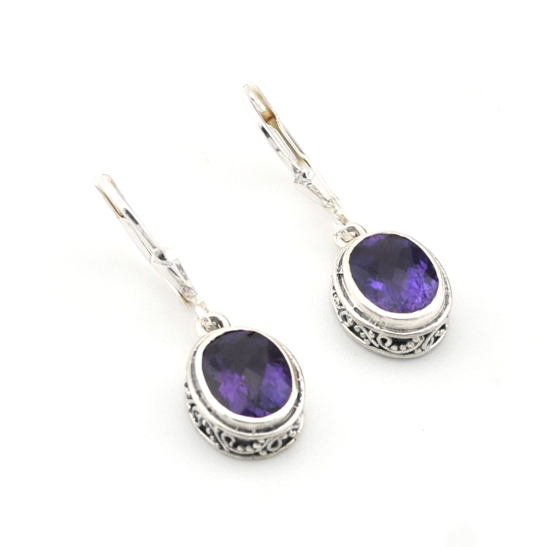 Silver earrings with purple gemstones on a white background