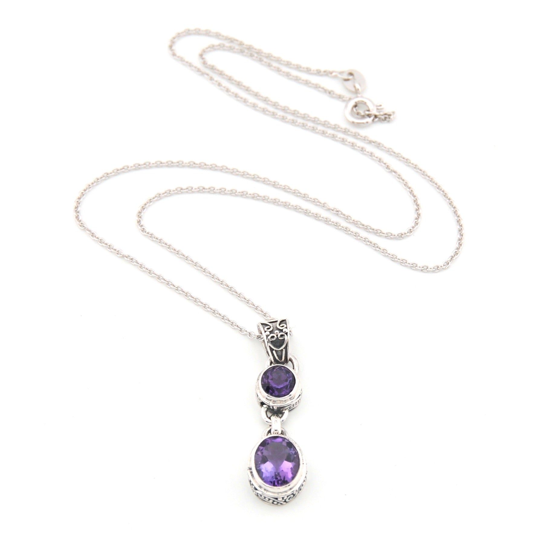 Silver necklace with purple gemstone pendant on a white background