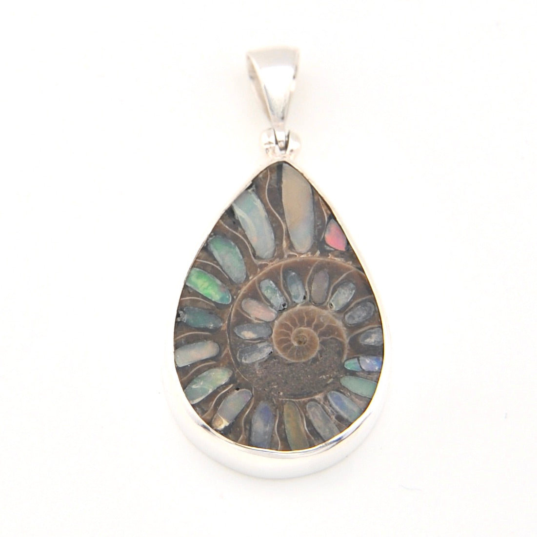 Teardrop-shaped pendant with multicolored stone and silver setting on a white background