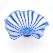 A scallop-shaped glass bowl with a blue and white striped pattern, photographed from a top-down angle on a white background.