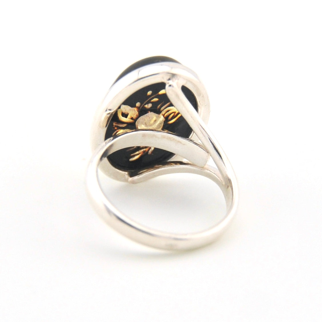 Silver ring with black and gold design on a white background