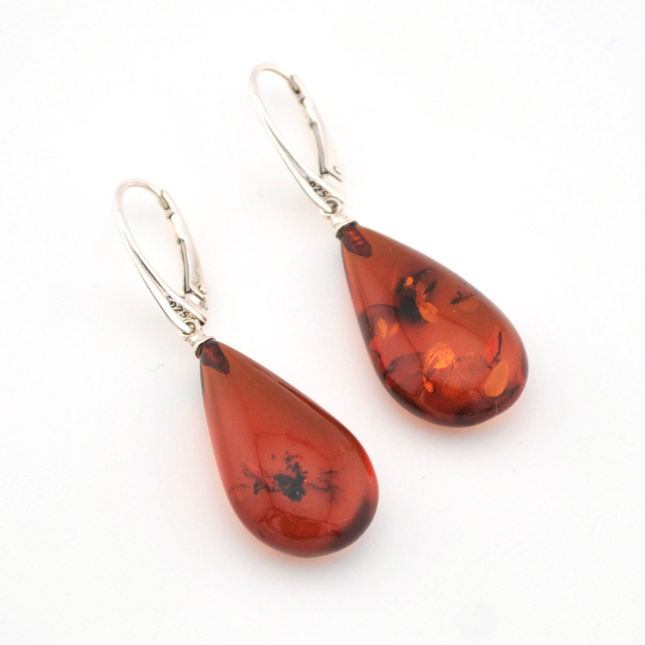 Teardrop-shaped amber earrings with silver hooks on a white background