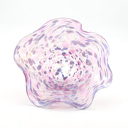 Glass bowl with a wavy design and purple and pink speckled pattern on a white background
