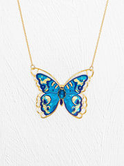 Butterfly-shaped pendant on a gold chain against a white background