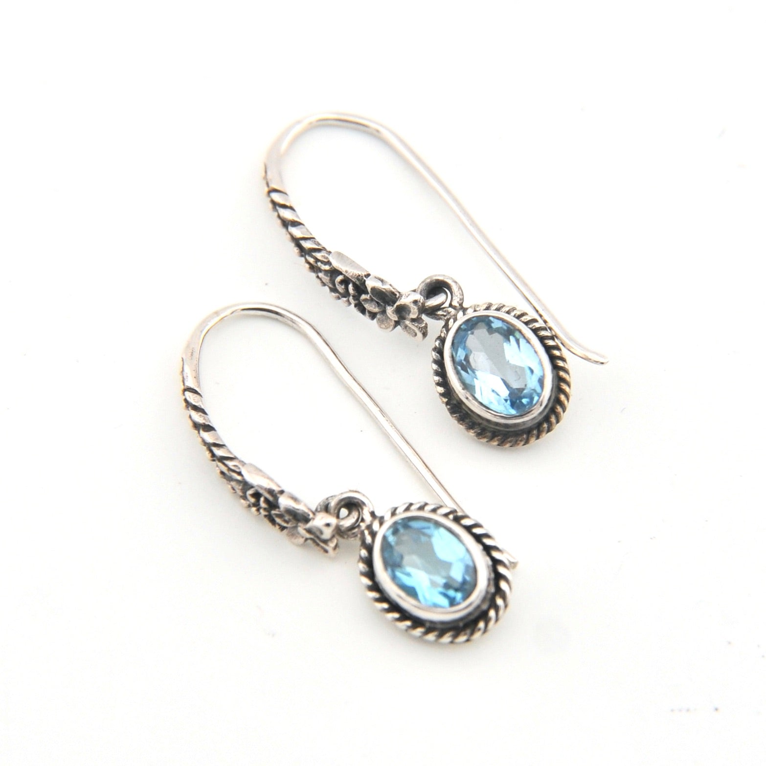 Silver earrings with blue gemstones on a white background