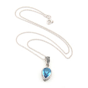 Silver necklace with a blue teardrop pendant on a white background