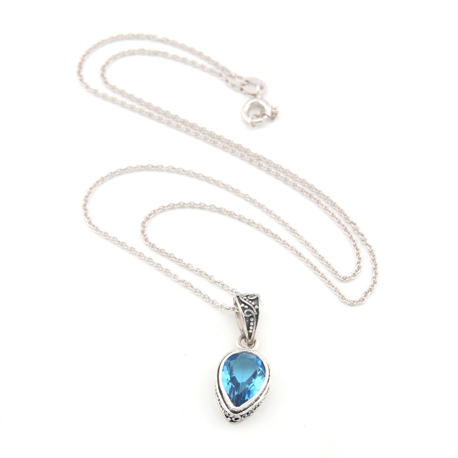 Silver necklace with a blue teardrop pendant on a white background