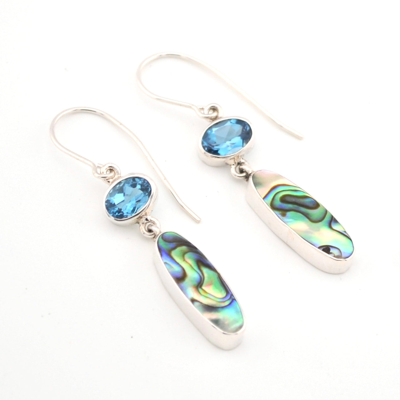 Silver earrings with blue gemstones and abalone shell on a white background