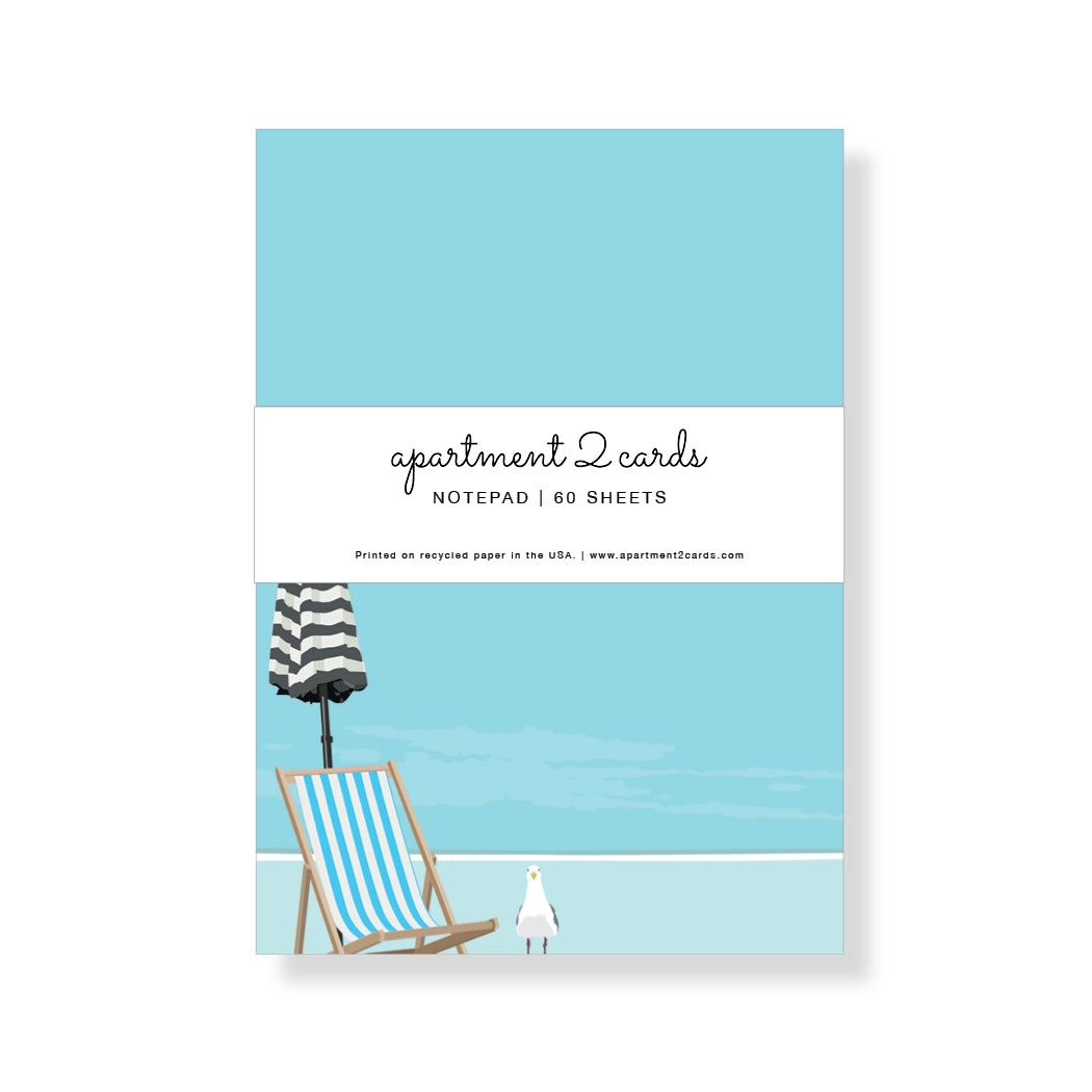 Notepad with beach scene design featuring a chair, umbrella, and seagull on a blue background.