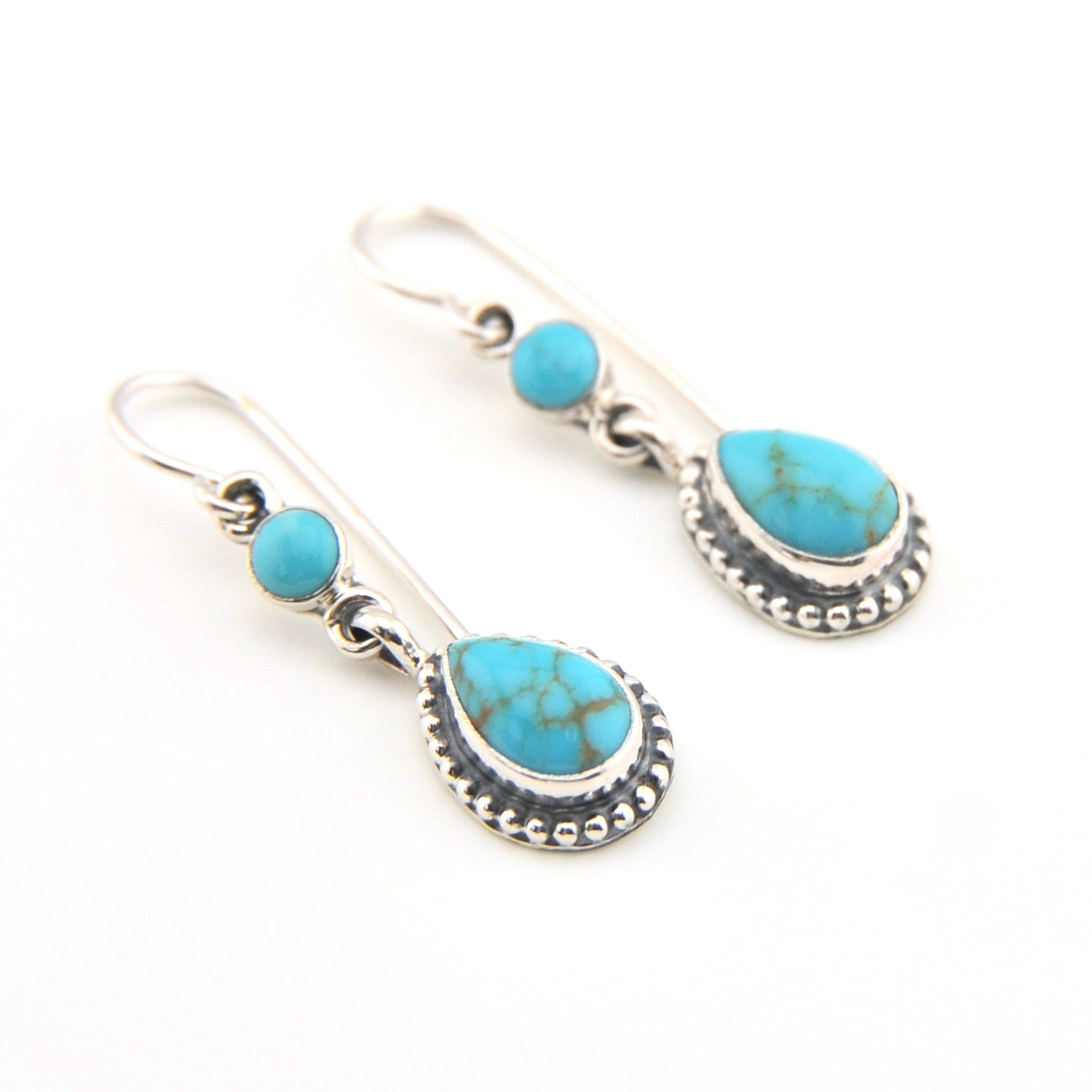 Turquoise and silver earrings on a white background