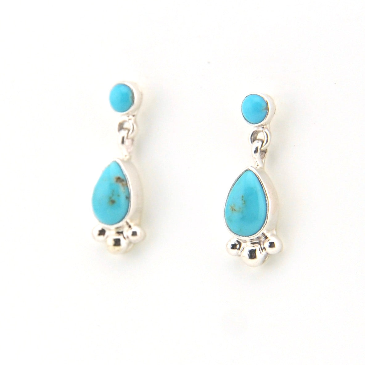 Turquoise teardrop earrings with silver accents on a white background