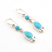 Pair of silver earrings with turquoise stones on a white background