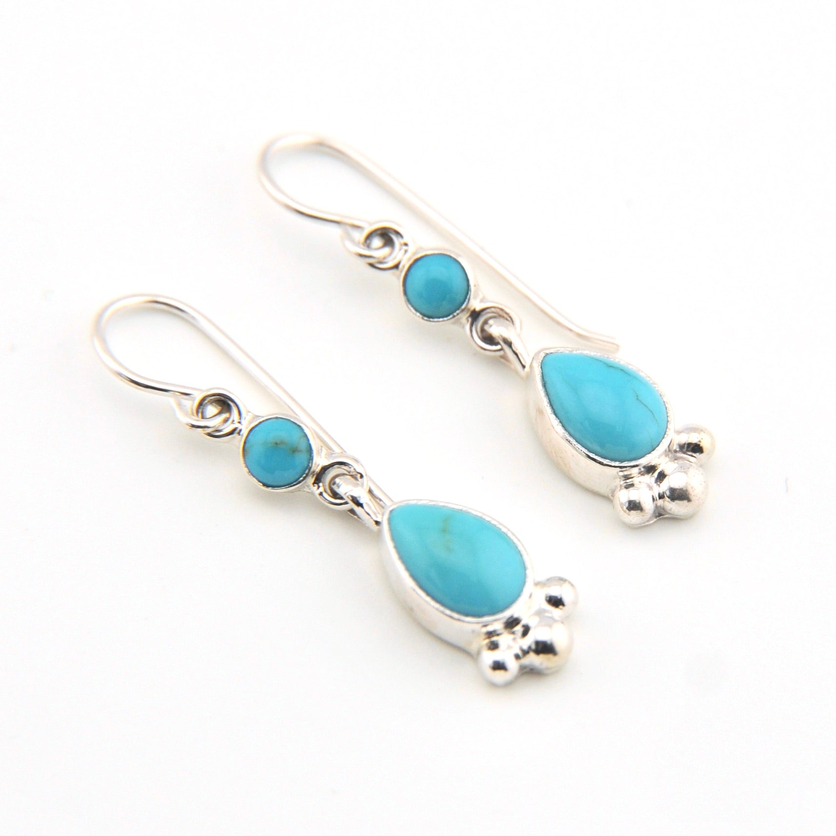 Pair of silver earrings with turquoise stones on a white background