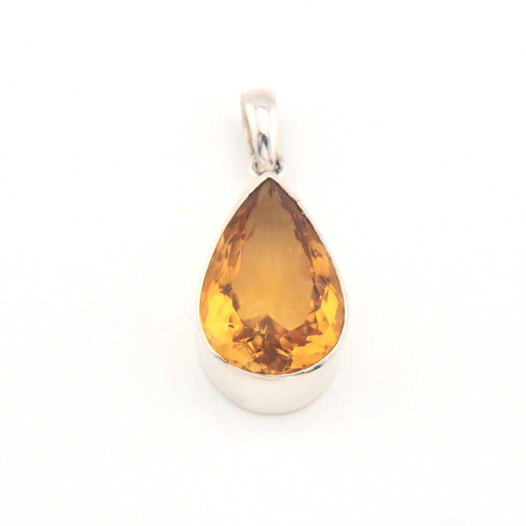 Teardrop-shaped citrine pendant on a white background
