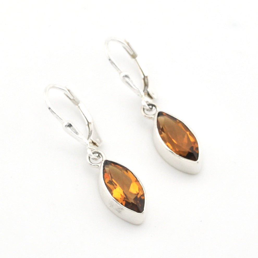 Silver earrings with amber-colored teardrop stones on a white background