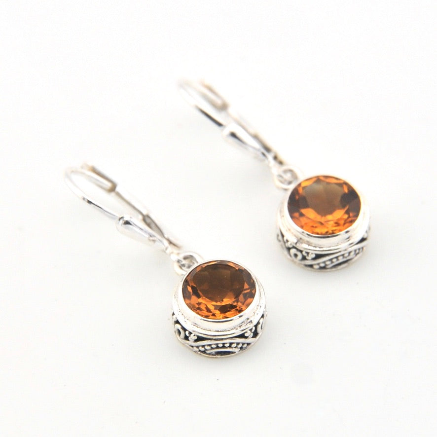 Silver earrings with round amber-colored gemstones on a white background