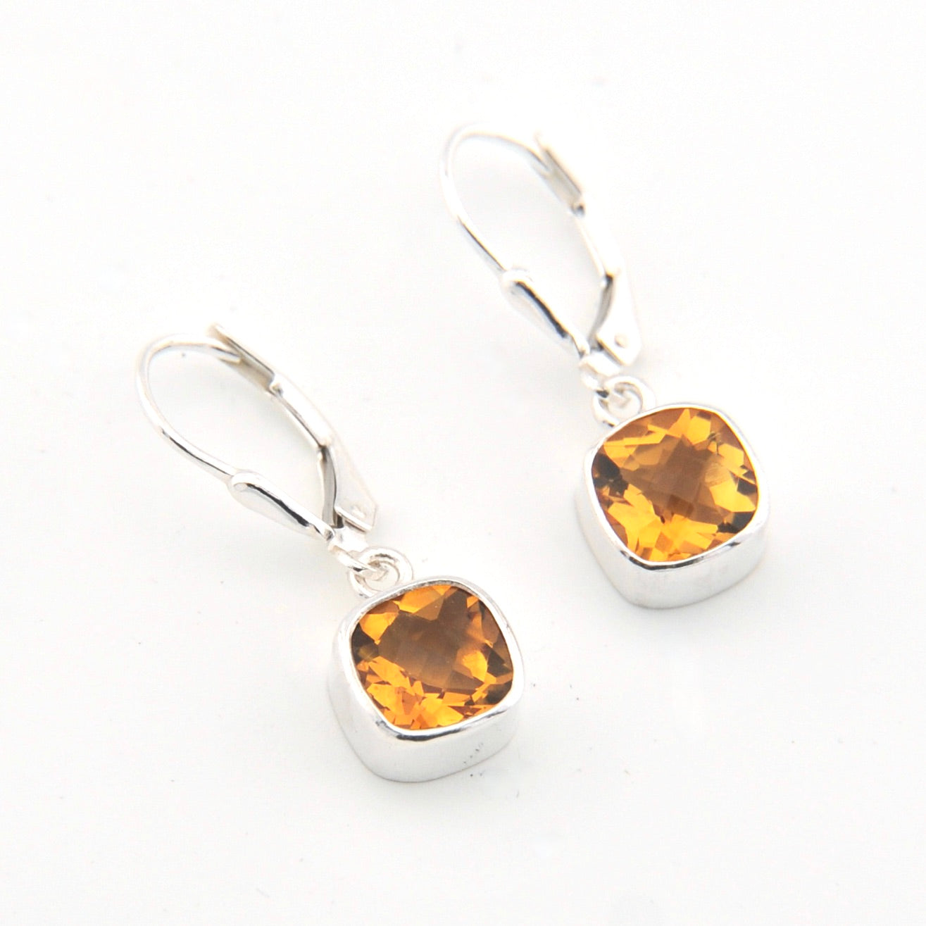 Silver earrings with amber-colored gemstones on a white background
