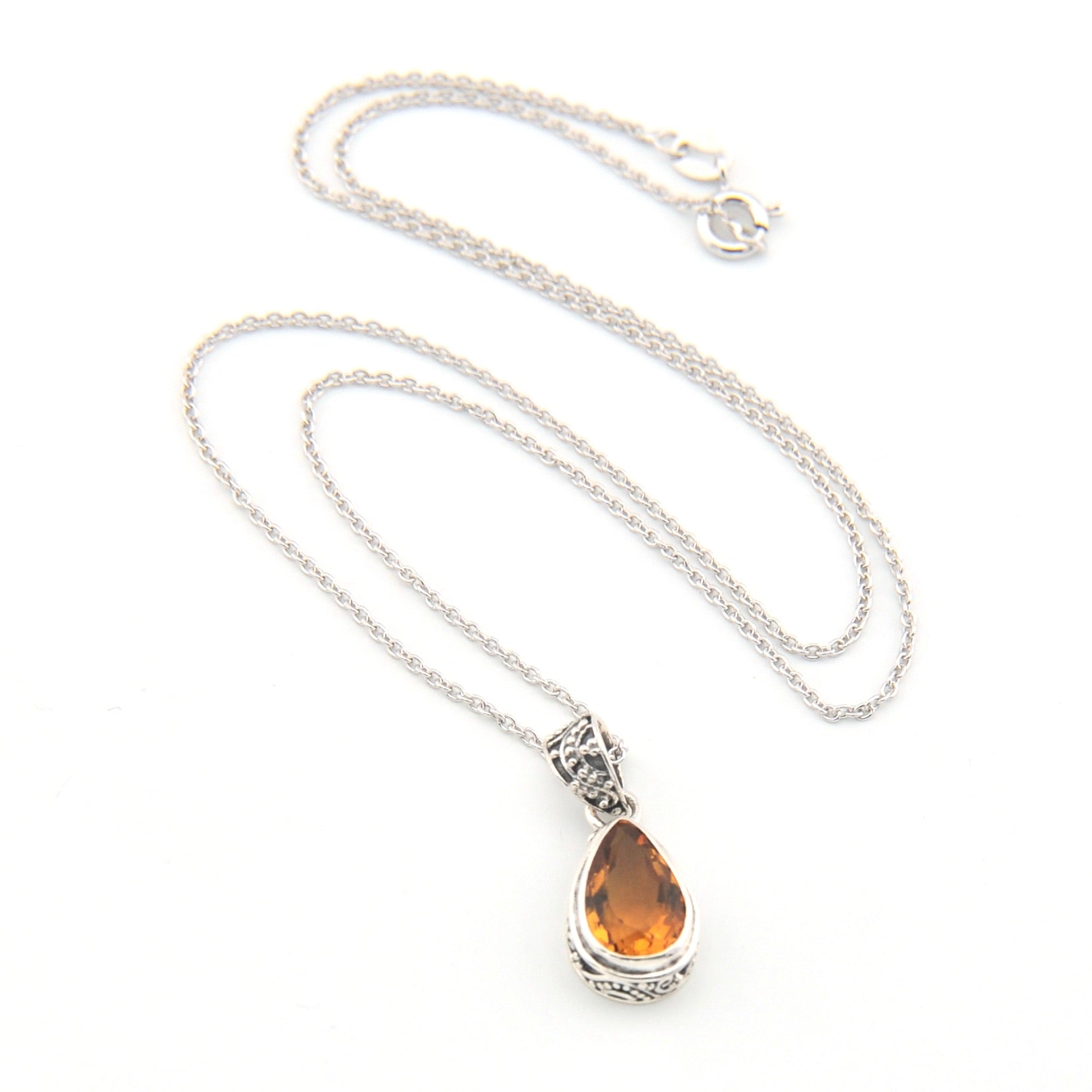 Silver necklace with a teardrop-shaped amber pendant on a white background
